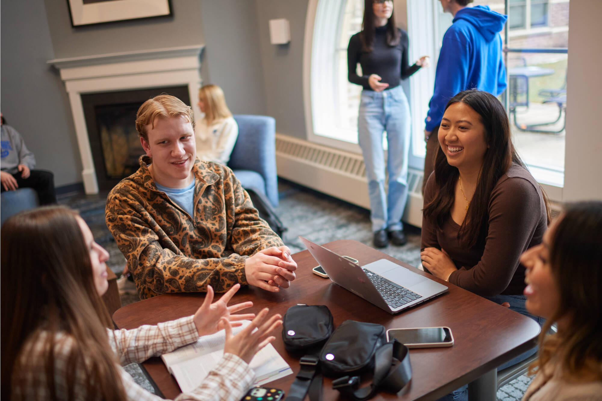 Students talk and collaborate around a table in a living center lounge.